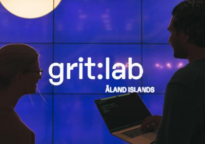 Två personer och blå skärm med texten grit:lab